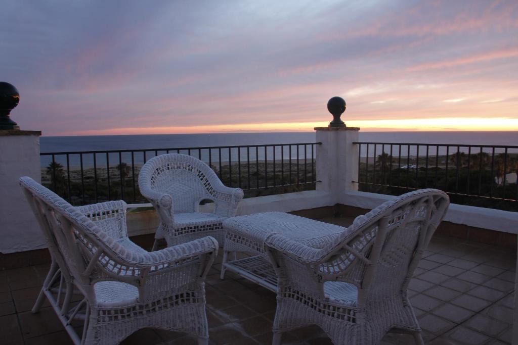 3 chaises et une table sur un balcon donnant sur l'océan dans l'établissement Sisos Place, à Zahara de los Atunes