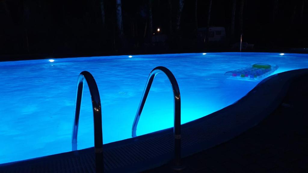 a swimming pool at night with blue lights in it at Apartament Orange Sun nr°7 in Pobierowo