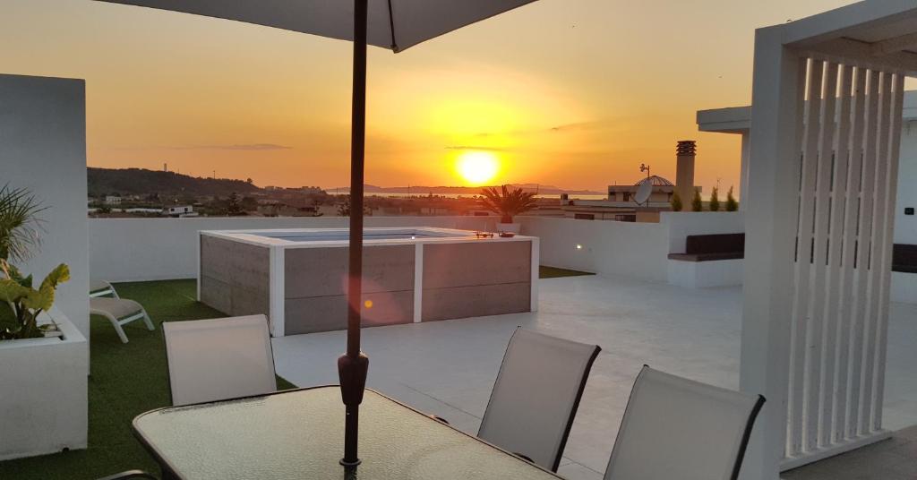 托雷格羅塔的住宿－L'isola di Ago，阳台上的一张桌子和一把遮阳伞,享有日落美景