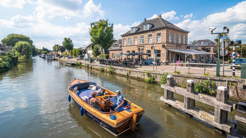 een groep mensen in een boot op een rivier bij Hotel Over de Brug in Haastrecht