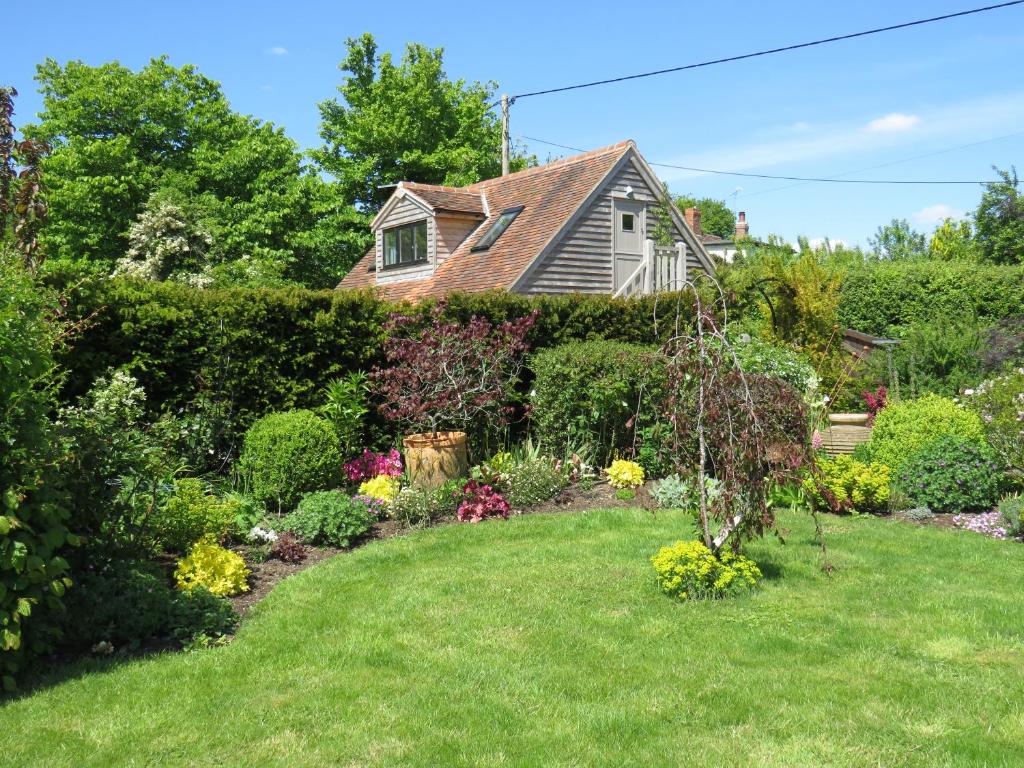 a yard with a garden of flowers and a house at The Loft at The Little Elms in Motcombe