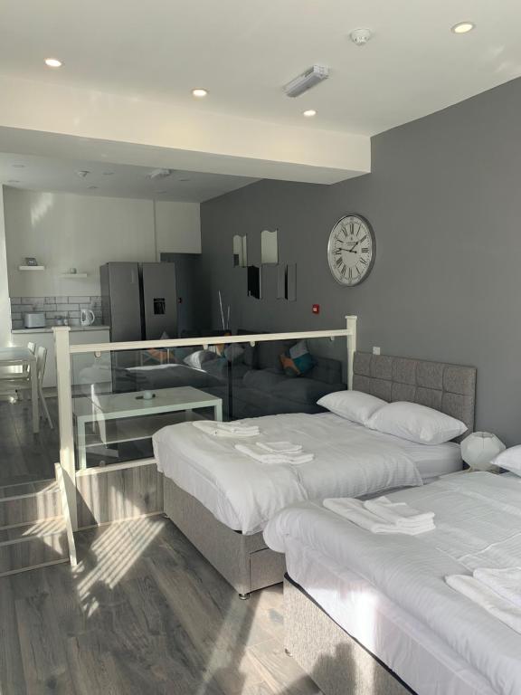ein Schlafzimmer mit 2 Betten und einer Uhr an der Wand in der Unterkunft Smeaton serviced Accommodation in Liverpool