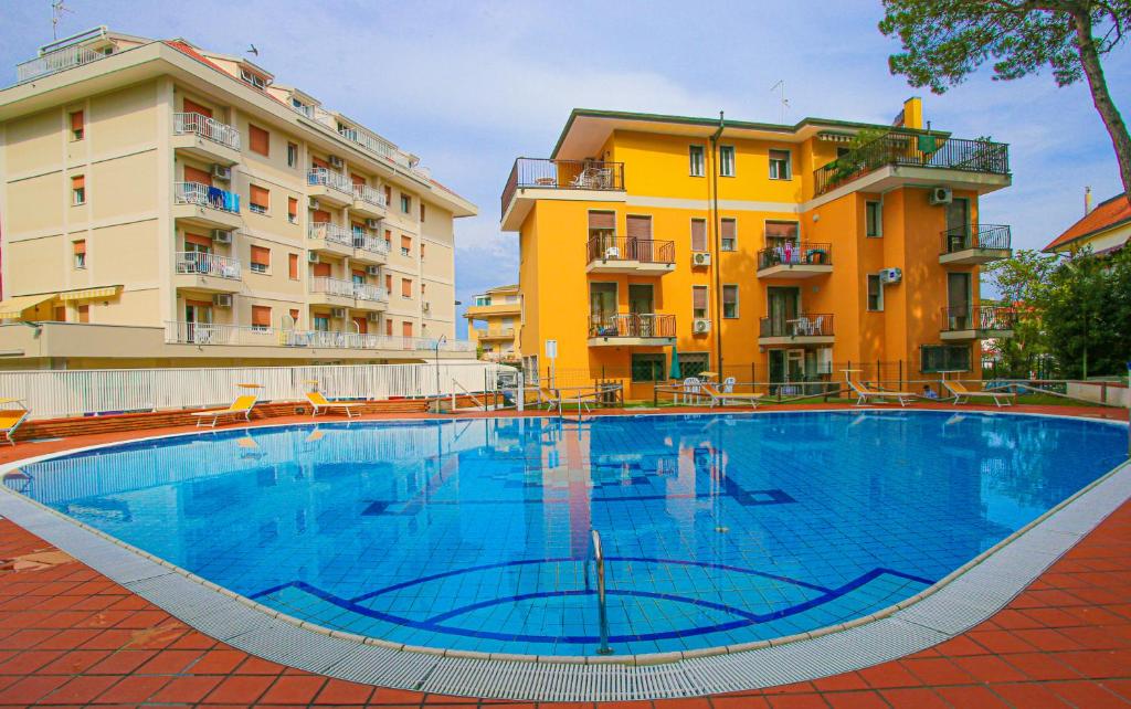 duży basen przed dwoma budynkami w obiekcie Residences La Rustica & Elite w mieście Eraclea Mare