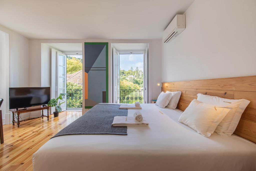 1 dormitorio con 1 cama blanca grande y TV en Casa da Pendoa, en Sintra