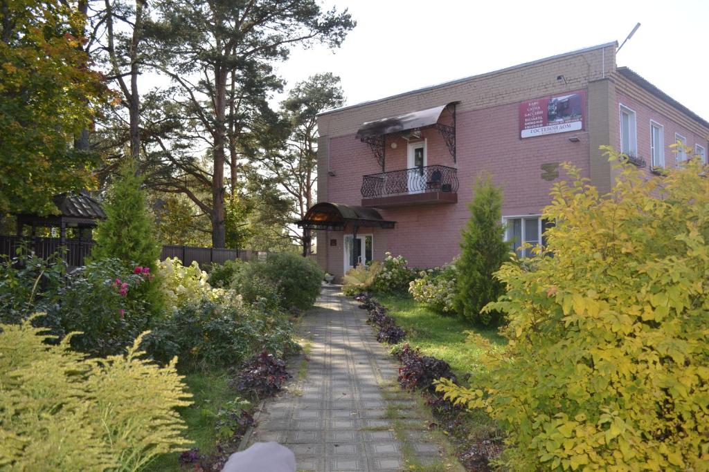 a walkway leading to a pink house with a balcony at Comfort Guest House in Myshkin