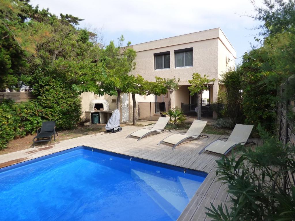 a swimming pool with chairs and a house at Villa T6, 10 couchages, front de mer, piscine, Saint Pierre la Mer in Saint Pierre La Mer
