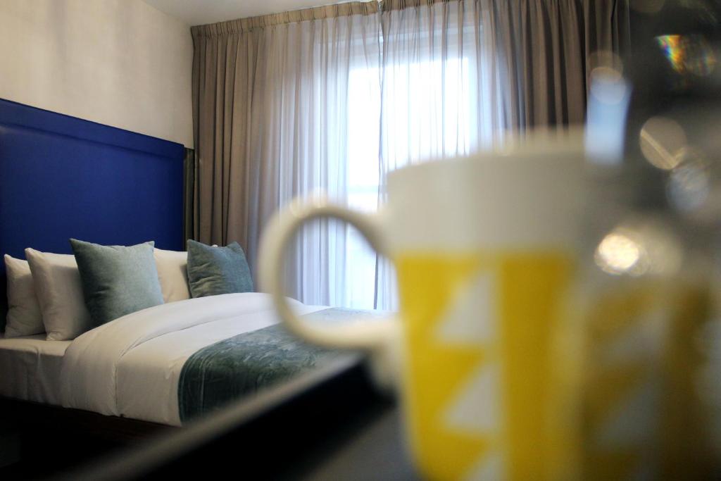 a hotel room with a bed and a glass of beer at CG Kensington in London