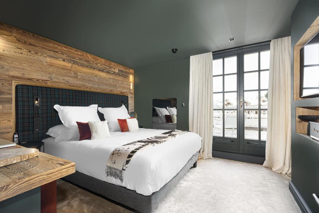 a bedroom with a large bed and a large window at Hotel Le Chabichou in Courchevel