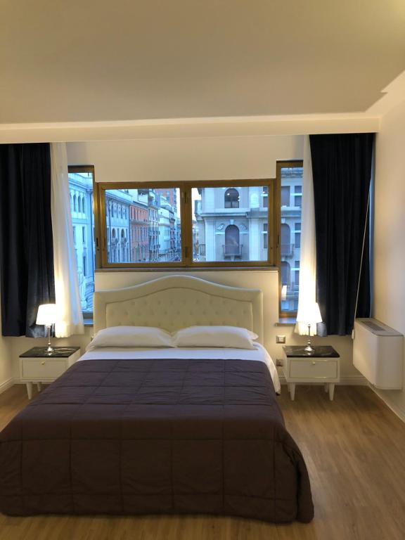 een slaapkamer met een groot bed en 2 ramen bij A&F Apartment Padova Piazza Garibaldi in Padua