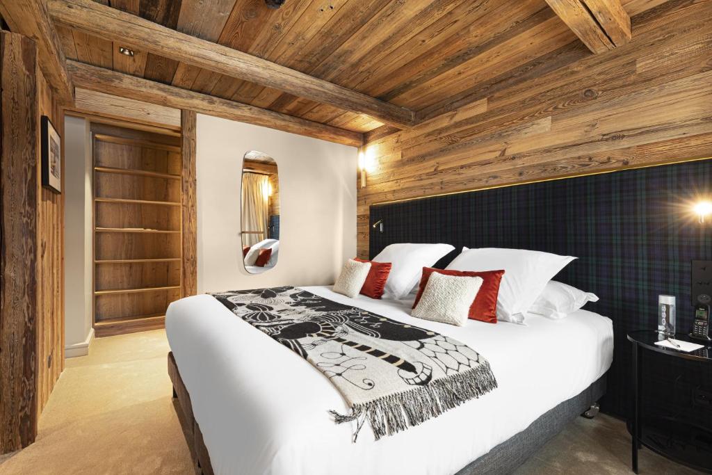 a bedroom with a large white bed with wooden ceilings at Hotel Le Chabichou in Courchevel