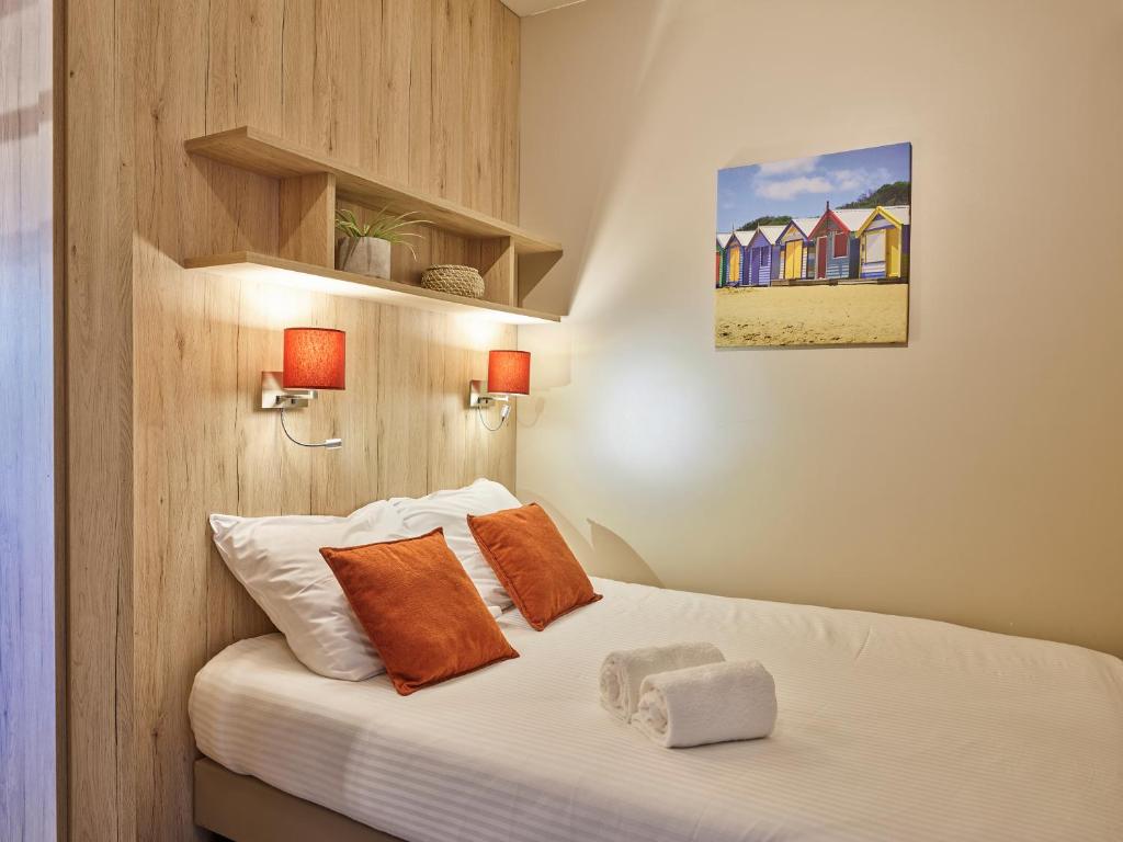 a bedroom with a bed with orange pillows at Holiday Suites Westende - Middelkerke in Middelkerke