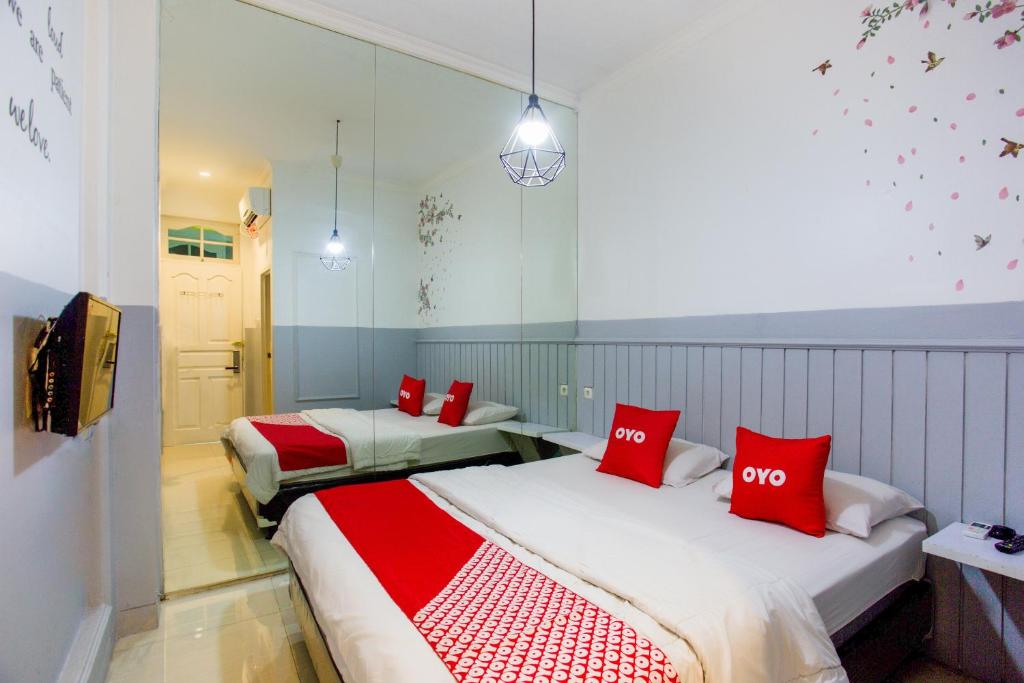 2 letti in una camera con cuscini rossi di OYO 3785 Kemayoran Residence a Giacarta