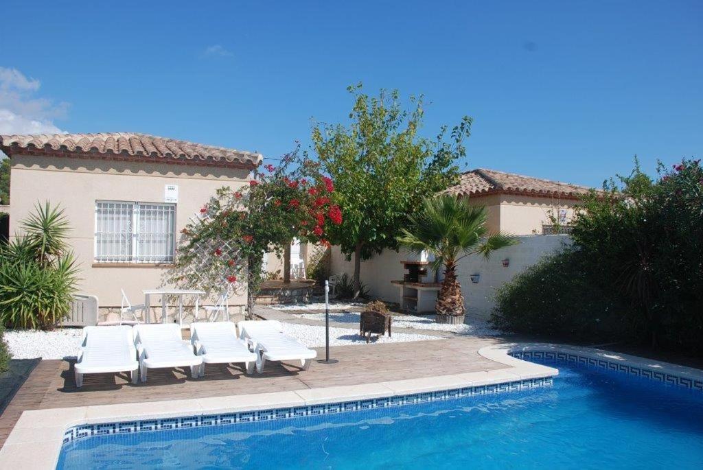 a villa with a swimming pool and chairs and a house at Chalet turistico Ametlla de Mar in Les tres Cales