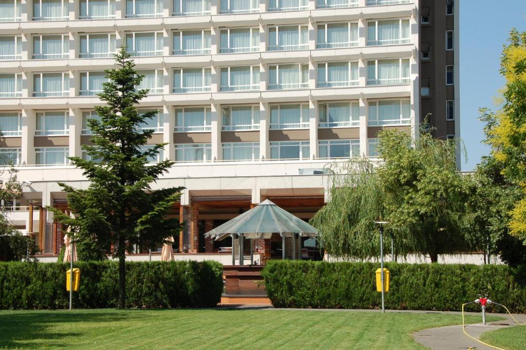 um edifício com um gazebo em frente em Ramada by Wyndham Bucharest Parc Hotel em Bucareste