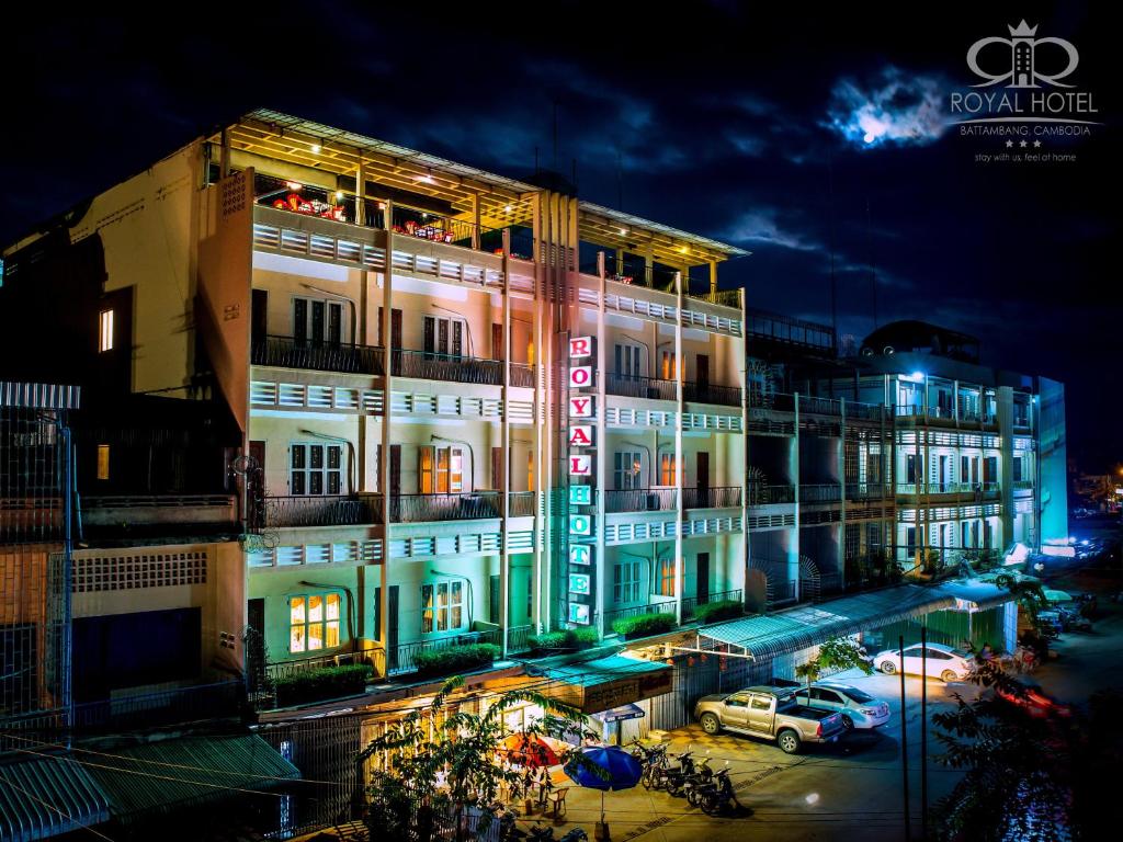 un edificio iluminado con coches estacionados frente a él en Royal Hotel en Battambang