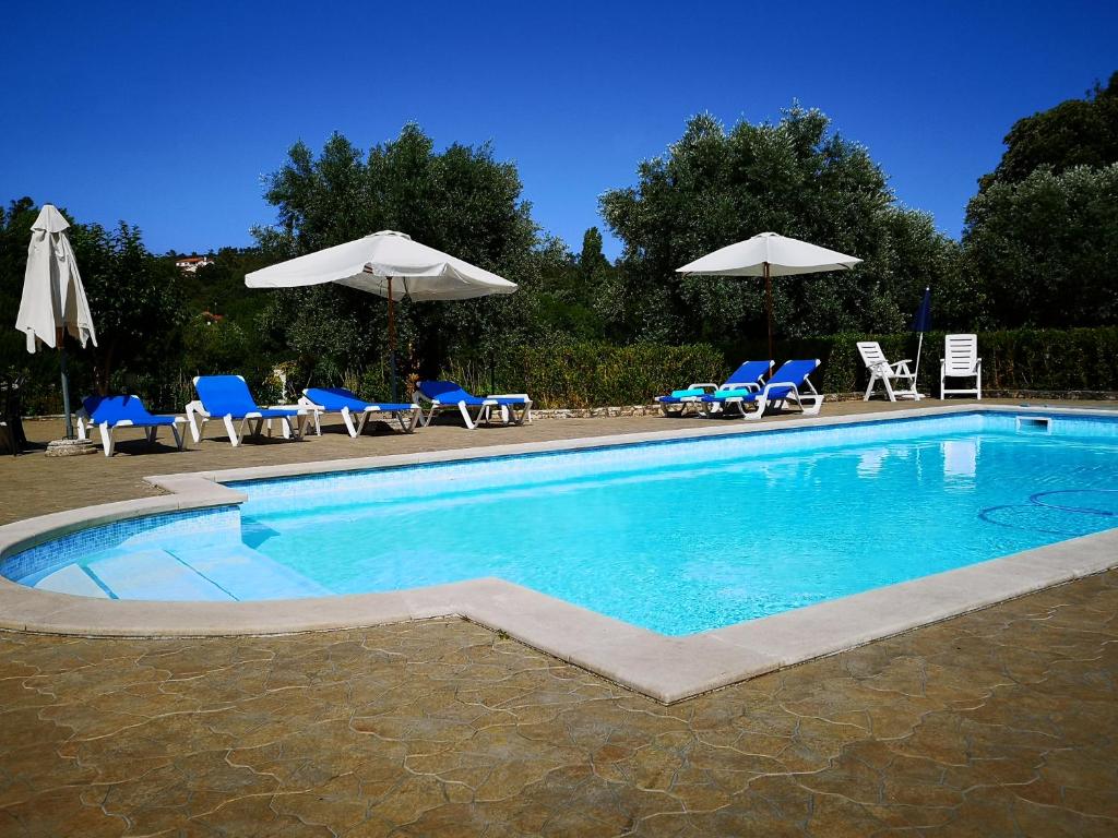 a swimming pool with blue chairs and umbrellas at Casal do Morgado, country house to relax in Formigais
