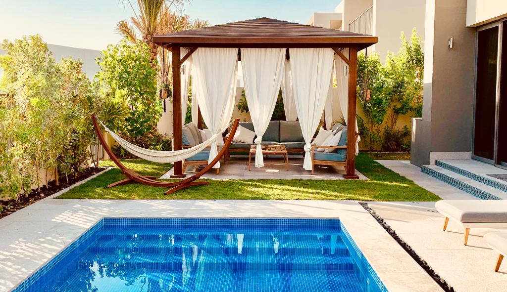 una hamaca y un cenador junto a una piscina en The Sunshine Villa, en Dubái