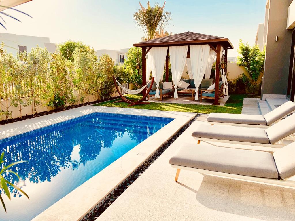 uma piscina com cadeiras e um gazebo em The Sunshine Villa no Dubai