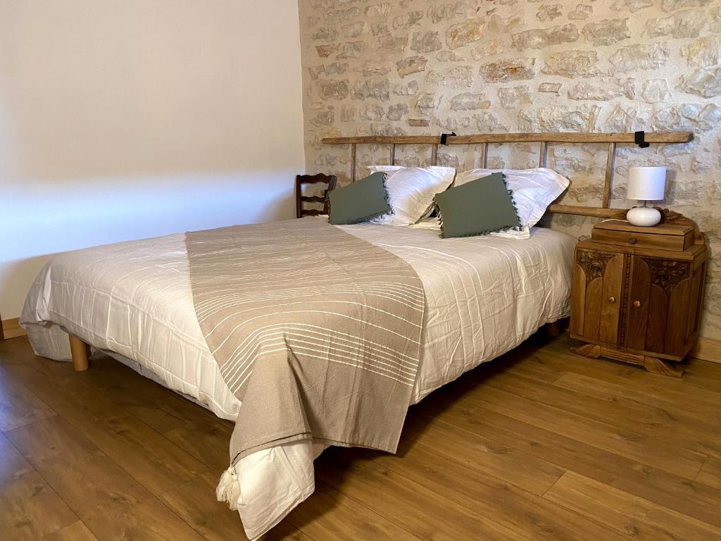 a bedroom with a bed and a stone wall at Clos De La Charnaille in Cousance