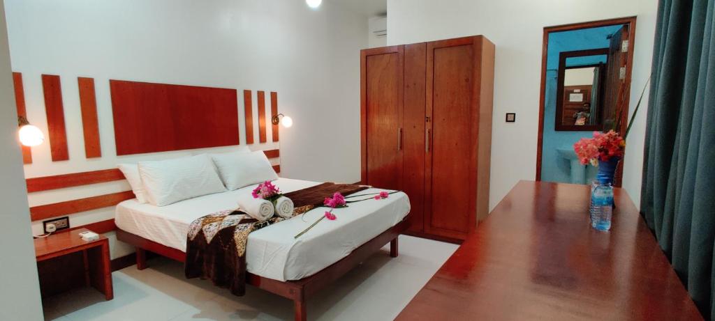 Un dormitorio con una cama y una mesa con flores. en Equator Holiday Inn en Fuvahmulah