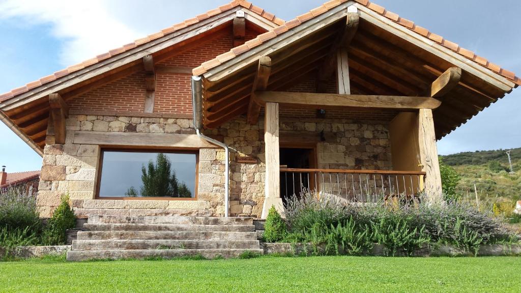 a stone house with a large window in a yard at Los Chozos de la Braña in Brañosera