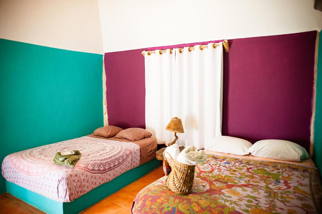 2 Betten in einem Zimmer mit Lila und Grün in der Unterkunft Nacional Beach Club & Bungalows in Mahahual