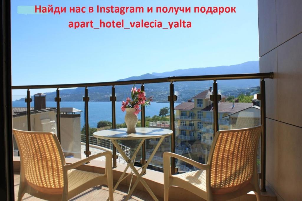 un balcón con 2 sillas y una mesa con flores. en ЖК Валенсия, en Yalta