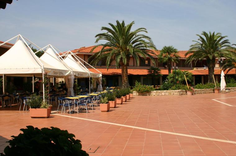 a resort with tables and chairs and palm trees at Residence Porto Coda Cavallo in San Teodoro