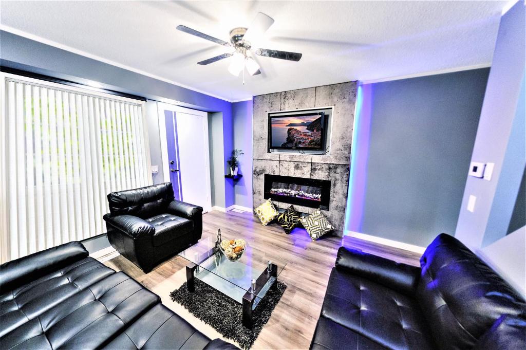 uma sala de estar com um sofá de couro preto e uma lareira em The Modern Spot em Winnipeg