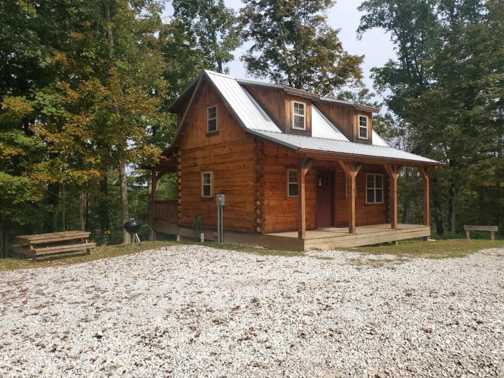 une cabane en rondins au milieu d'une allée de gravier dans l'établissement The Hampton - An Amish Built Deluxe Log Cabin, à Genoa