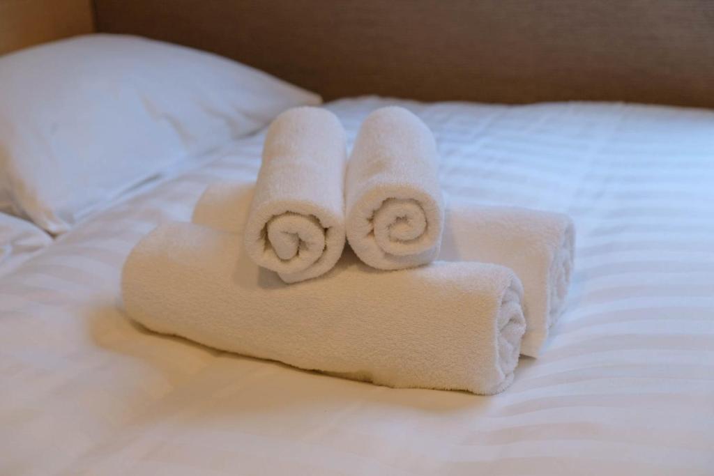 two rolled towels sitting on top of a bed at The Light Inn - Vacation STAY 94704 in Tokyo