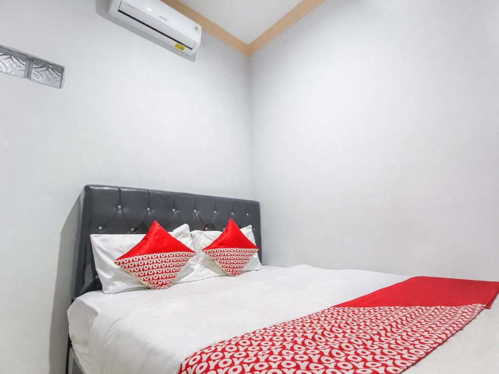 um quarto com uma cama com almofadas vermelhas e brancas em OYO 3399 Gea Guest House em Palimbão