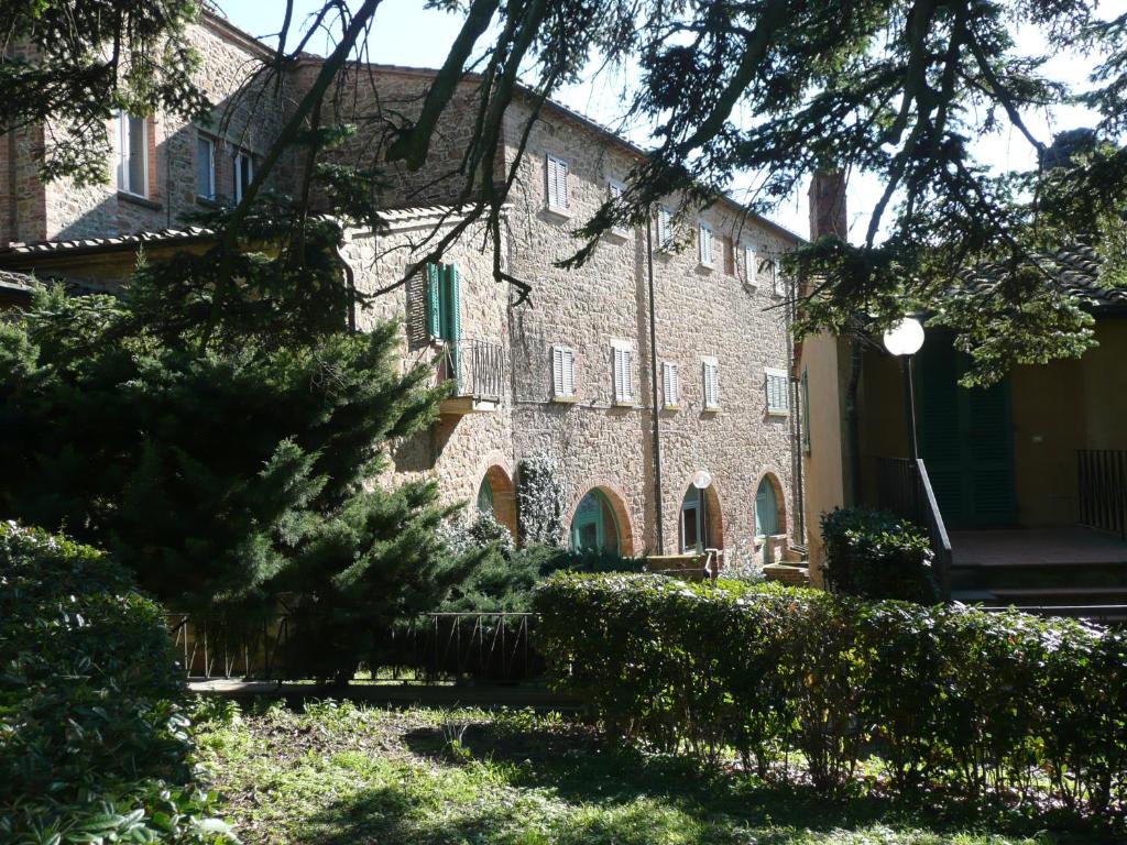 een groot bakstenen gebouw met een boom ervoor bij Il Gelsomino in Castelfalfi