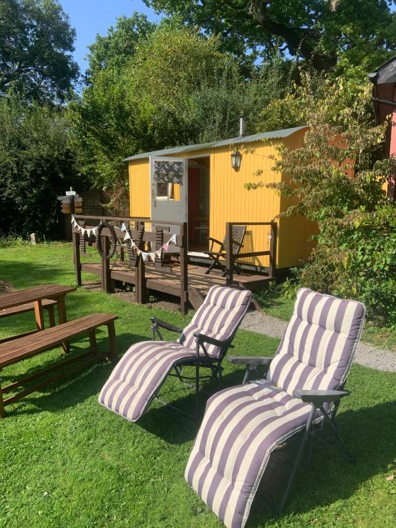 two chairs and a bench in a yard with a house at The Hideaway at Duffryn Mawr Self Catering Cottages in Cowbridge