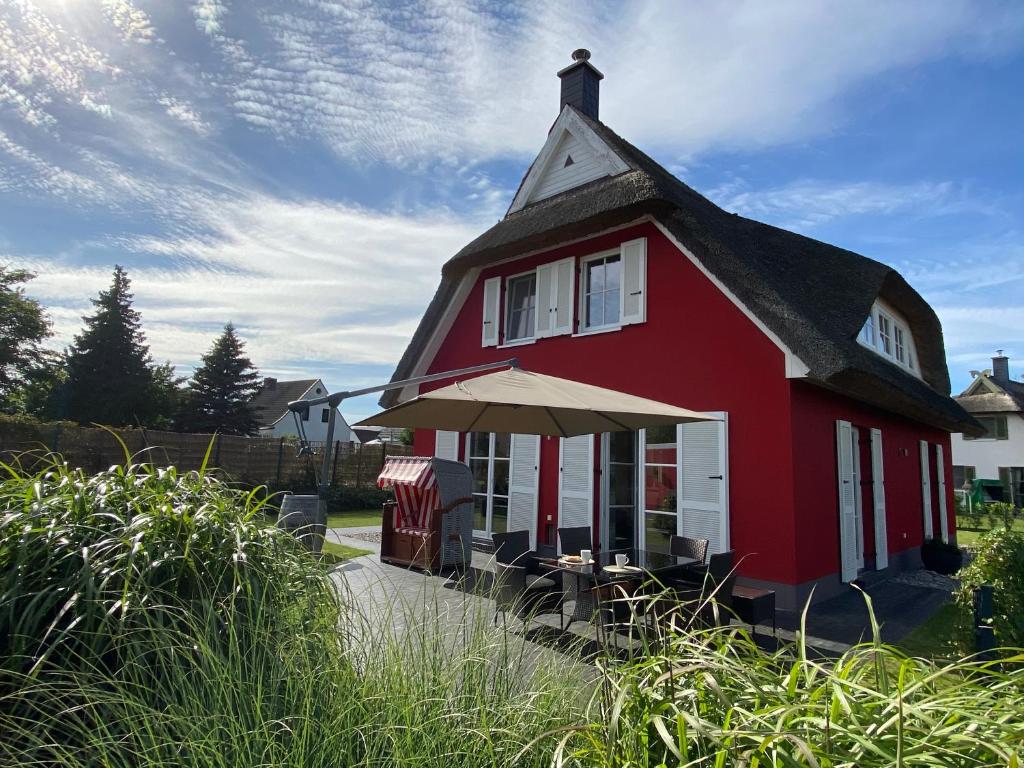 ein rotes Haus mit schwarzem Dach in der Unterkunft Fischer's Ferienhaus Rügen mit Sauna und Kamin in Ummanz