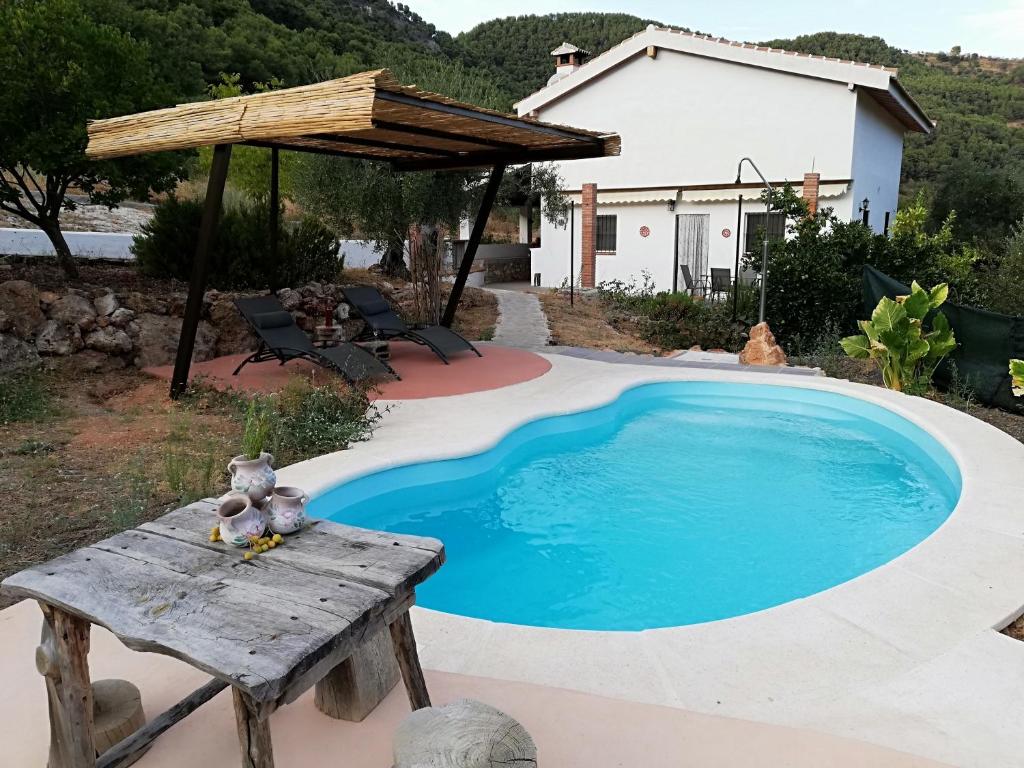 una pequeña piscina con una mesa de madera y un banco en Alojamiento Rural Alfaguara en Tolox