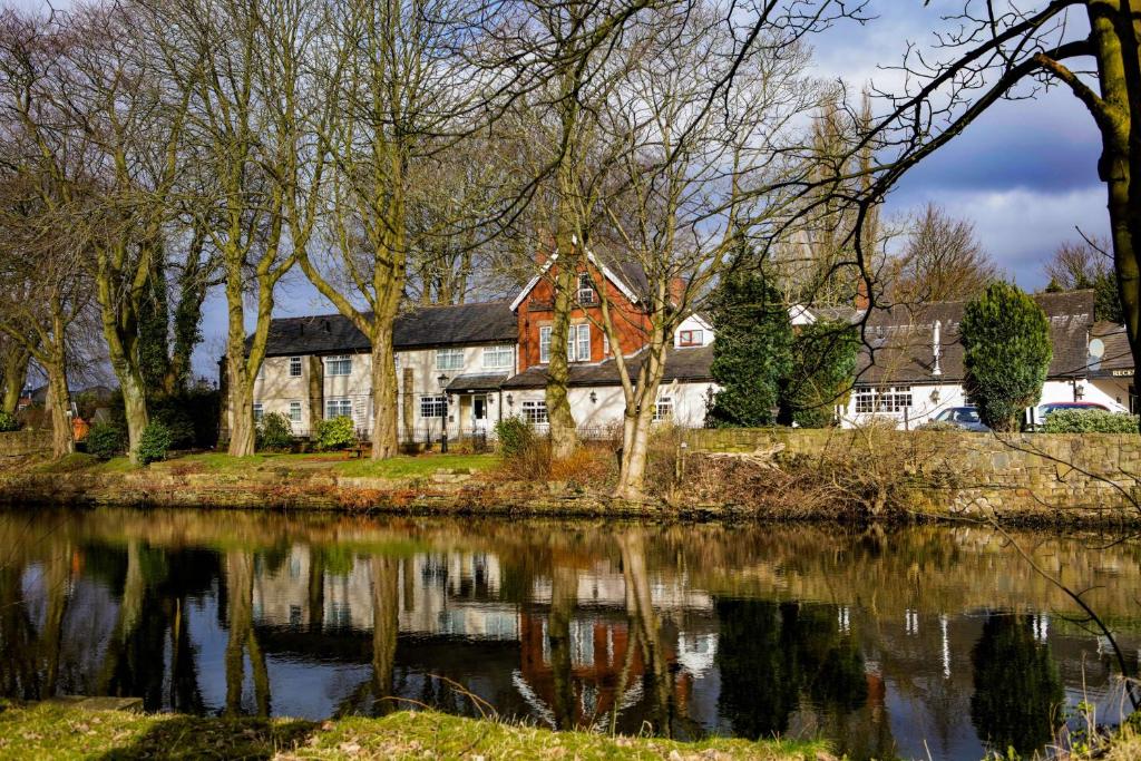 a house next to a body of water at Best Western Bolholt Country Park Hotel in Bury