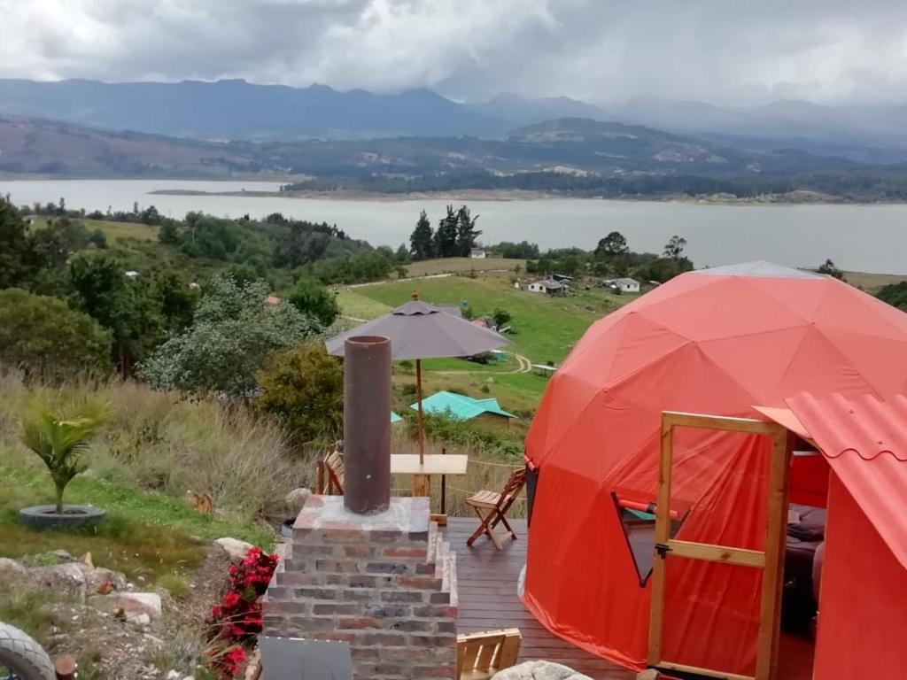 a red tent with a table and a view of a lake at Glamping Cabaña San Martin in Guatavita