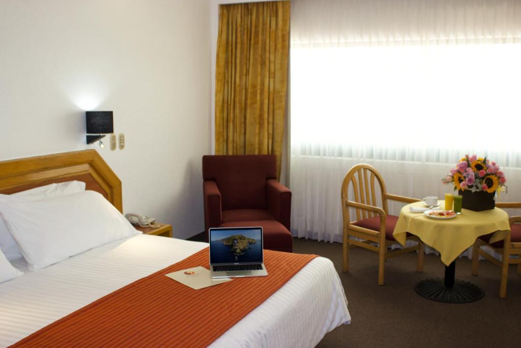 a hotel room with a bed and a laptop on a table at San Juan Park Hotel in San Juan del Río