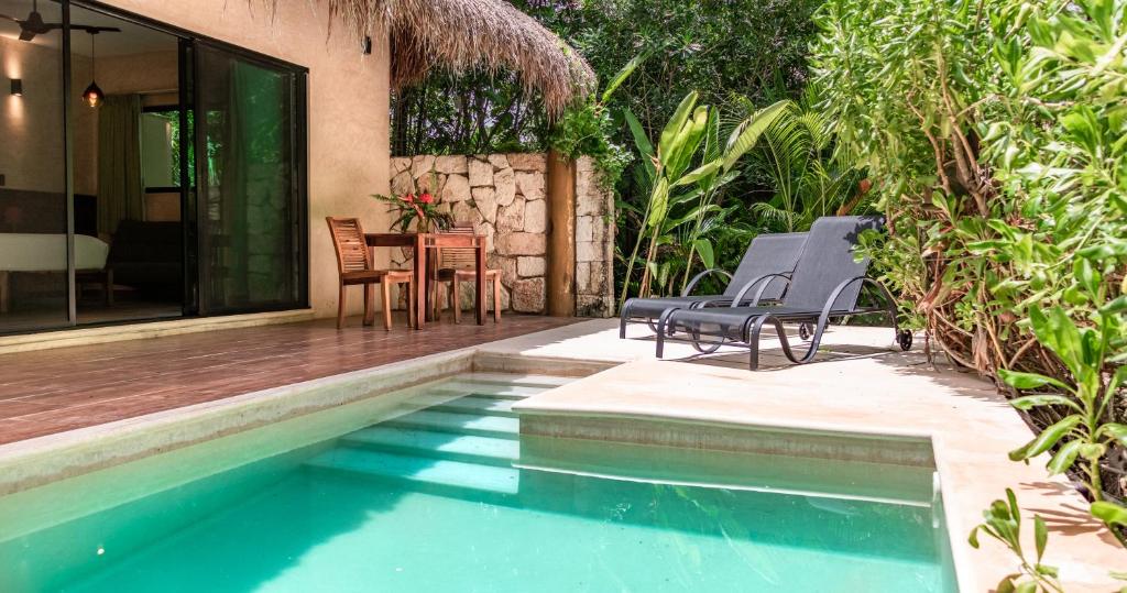 a swimming pool with two chairs and a table at Aldea Coba An Escape Boutique Experience in Cobá