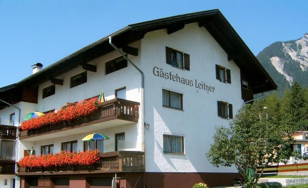 a building with red flowers on the balconies of it at Pension Leitner in Hofen