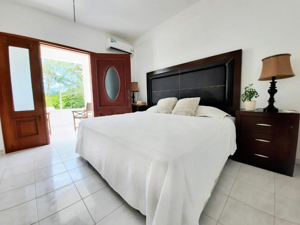 - une chambre avec un grand lit blanc et une grande fenêtre dans l'établissement Casa Quintal - Cerca del mar, à Cancún