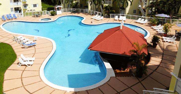 una grande piscina con ombrellone e sedie rossi di Zander's Paradise @Mystic (Full) a Ocho Rios