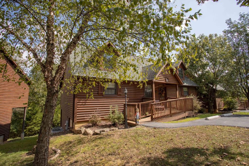 a log house with a porch and a tree at Ozarks Oasis cabin in Branson
