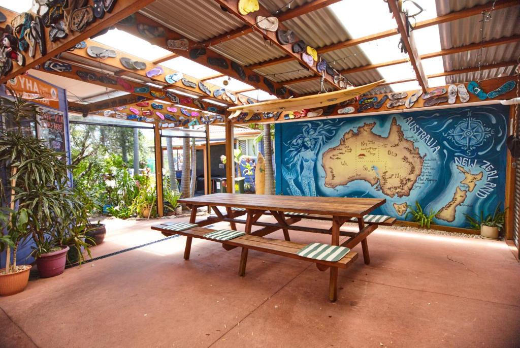 a picnic table in front of a wall with a map at Ozzie Pozzie Backpackers - Port Macquarie YHA in Port Macquarie