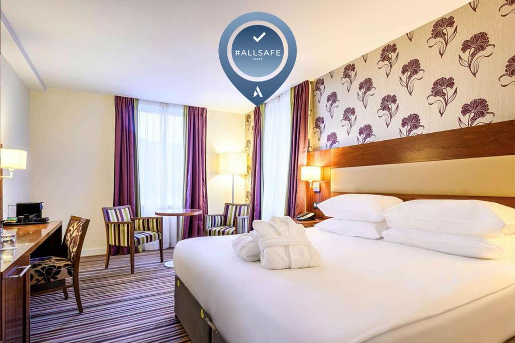
a hotel room with a large bed and a large window at Mercure Liege City Centre in Liège
