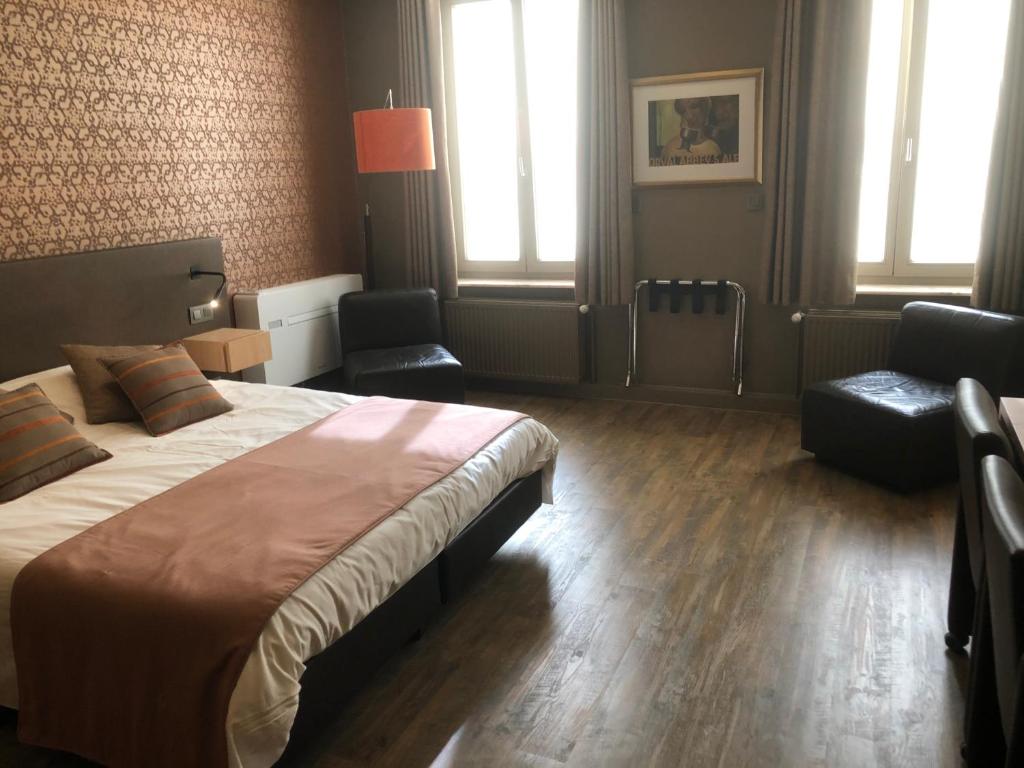 a bedroom with a large bed and two chairs at Hotel Duivels Paterke Harelbeeksestraat 29, 8500 Kortrijk in Kortrijk