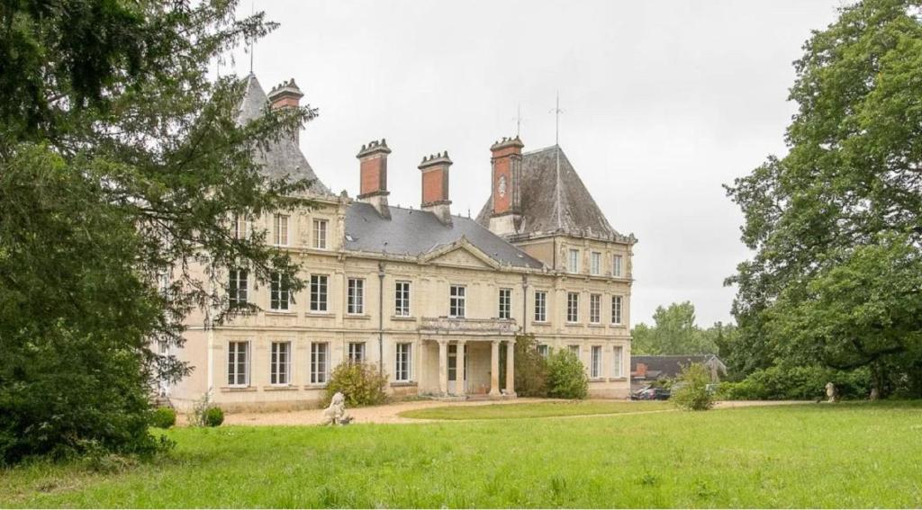 stary dom z dachem na zielonym polu w obiekcie Chateau L' Escale w mieście Saint-Herblon