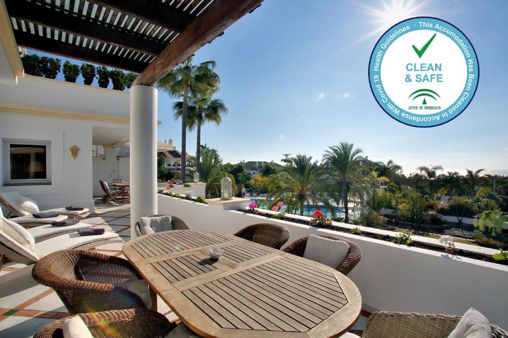 eine Terrasse mit einem Holztisch und Stühlen auf dem Balkon in der Unterkunft Monte Paraiso Apt in Marbella