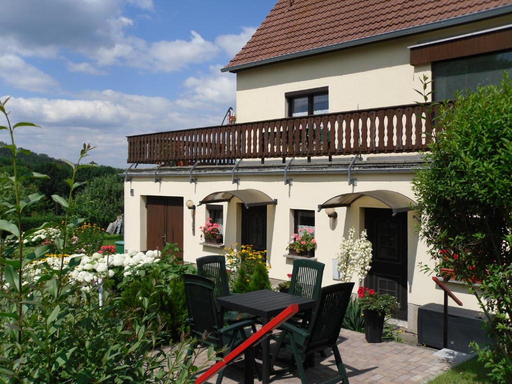 um pátio com uma mesa e cadeiras em frente a uma casa em Ferienwohnung Hartmann em Papstdorf